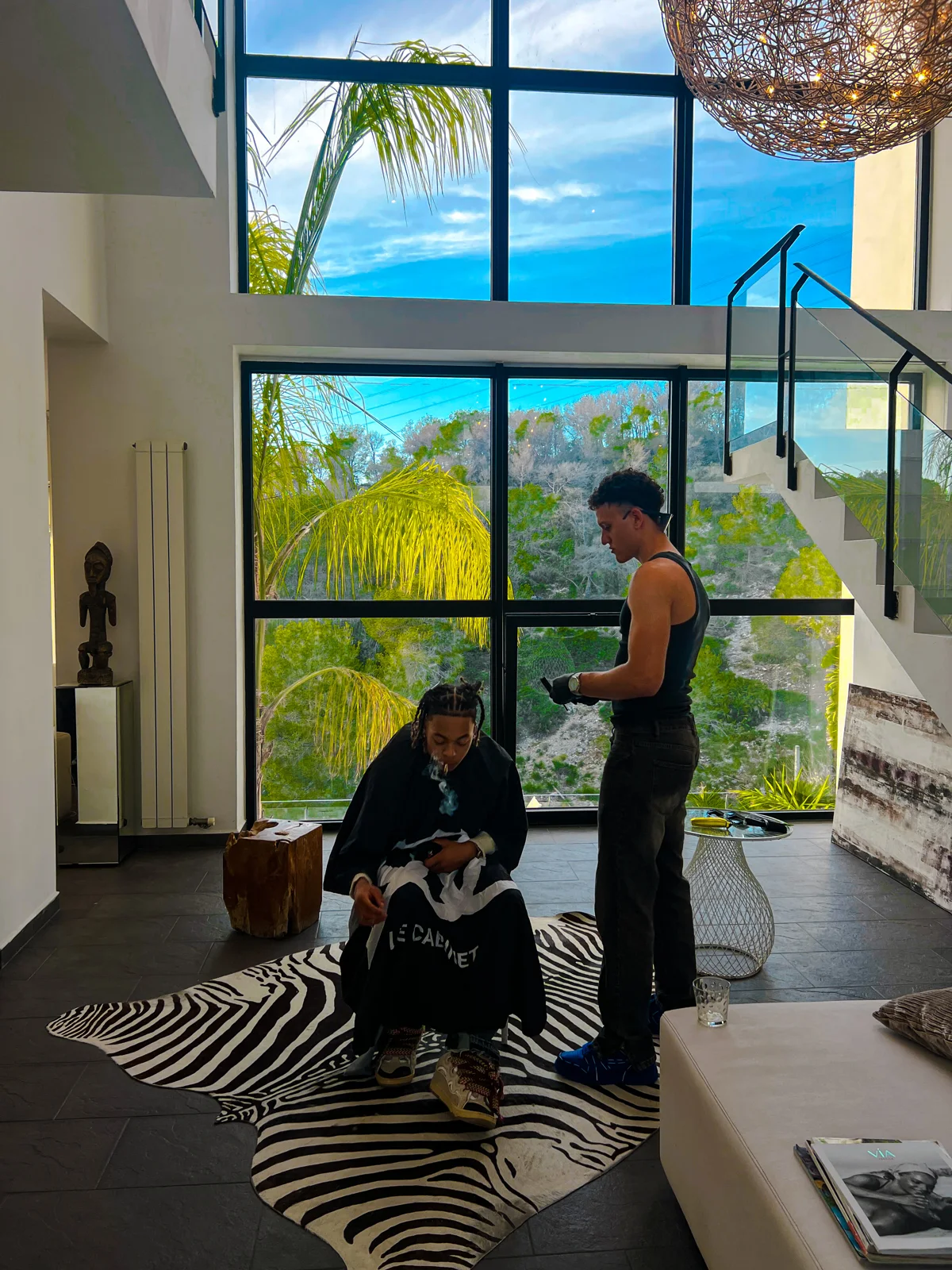 Mehdi et son client devant la baie vitrée ouverte sur les palmiers.